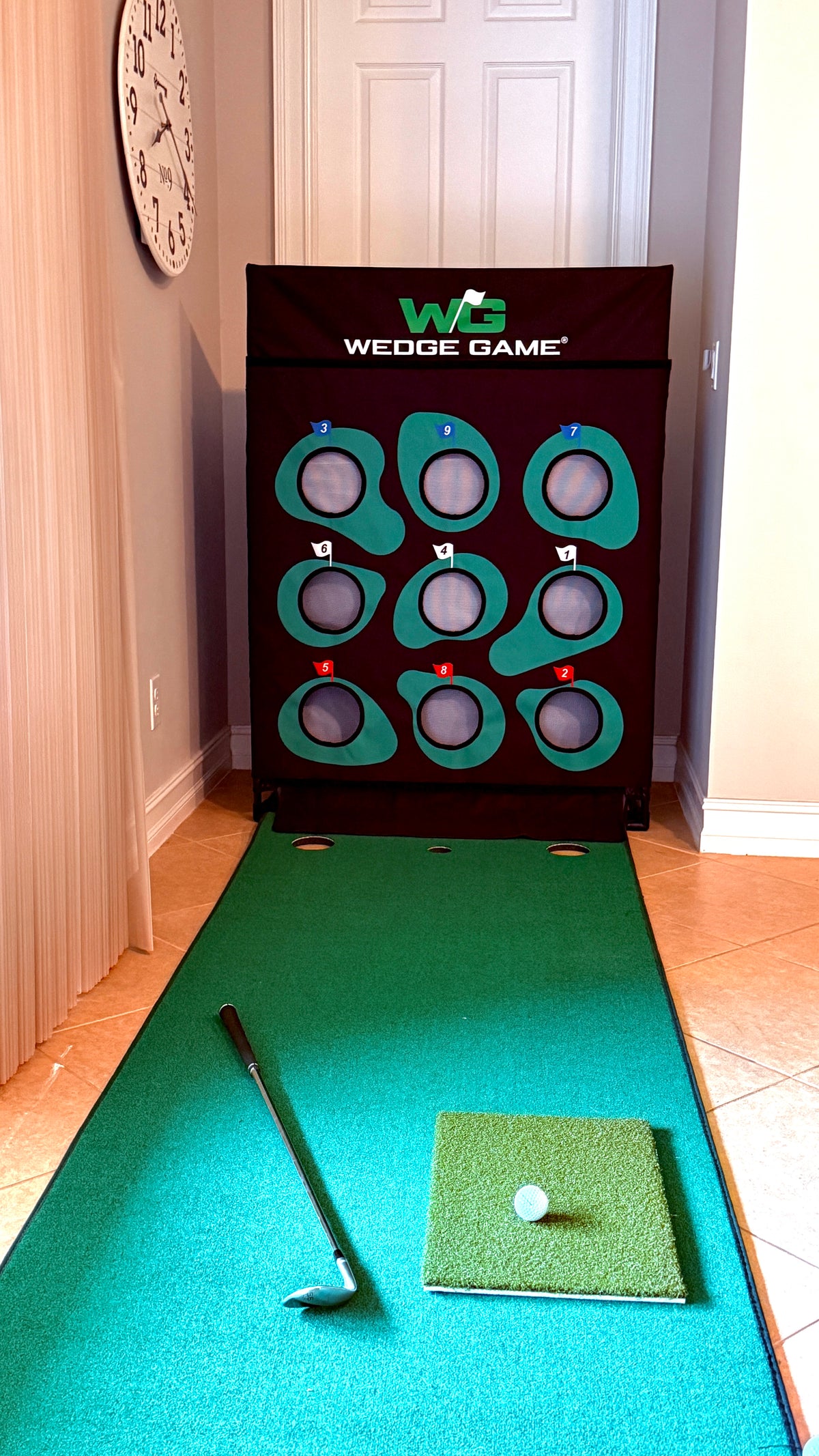 Wedge Game in front of a door in  home with a wedge, golf ball and chipping mat