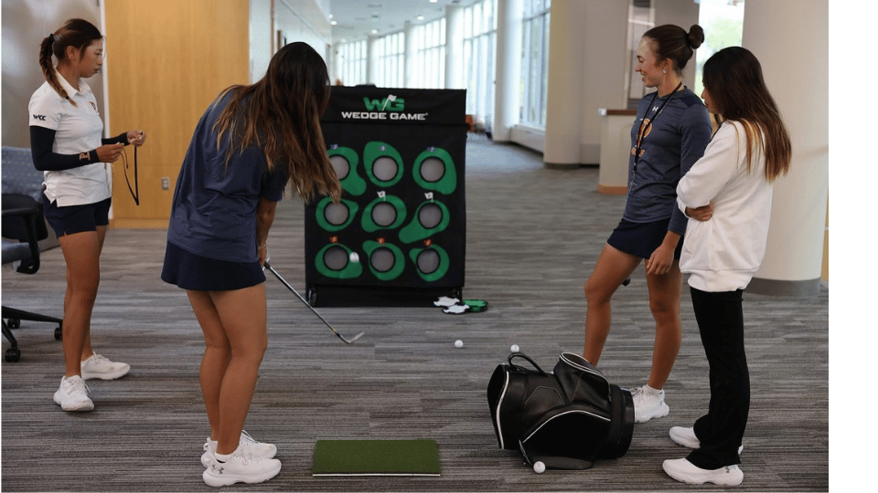 Golfers chipping at the Wedge Game 9-Hole Challenge net indoors